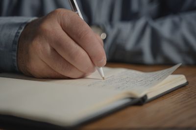 A hand writing notes with a pen in an open notebook.