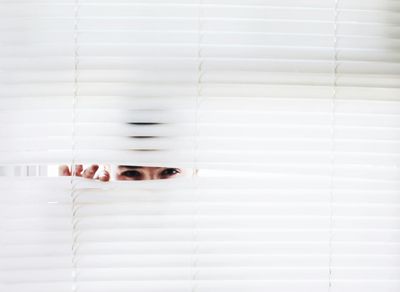 A man lurking behind closed blinds.