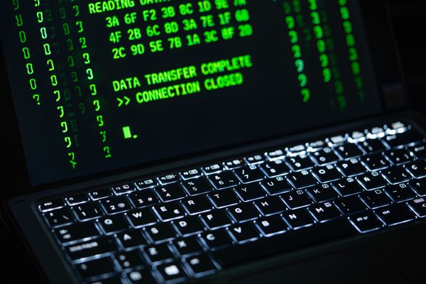 A green terminal screen reading Data Transfer Complete and Connection Closed above a backlit keyboard.