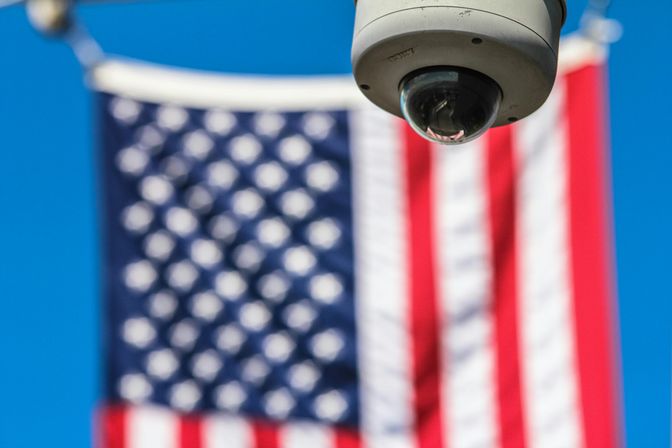 Surveillance camera focusing on security with American flag backdrop.